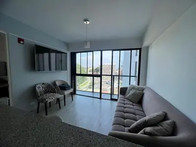 a living room with a couch and a large window at Departamento cerca al mar con terraza panoramica in Lima
