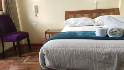 a bedroom with a bed with towels and a chair at San Blas B&B in Cusco
