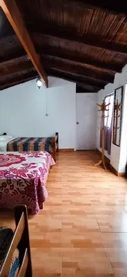 a bedroom with two beds and a wooden floor at La Viña de OsCar in Nuevo Imperial