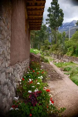 a stone wall with flowers next to a building at Unu Samay Lodge in Urubamba