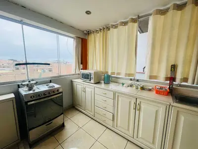 a kitchen with a stove and a microwave and windows at Las palmeras in Lima