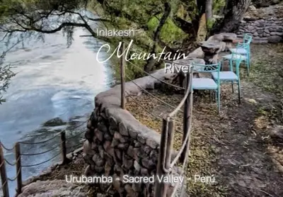 a stone wall with chairs next to the water at Tiny Mountain River in Urubamba