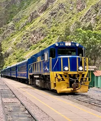 a blue and yellow train traveling down the tracks at Tiny Mountain River in Urubamba