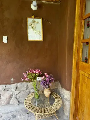a table with a vase with flowers on it at Casa Nuestra in Urubamba