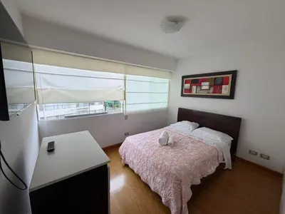 a bedroom with a bed and a table and a window at Duplex en miraflores av larco 1010 in Lima