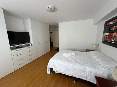 a white bedroom with a bed and a flat screen tv at Apartamento con ascensor en segundo piso, Miraflores in Lima