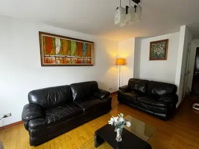 a living room with black leather couches and a table at Apartamento con ascensor en segundo piso, Miraflores in Lima