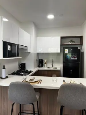 a kitchen with white cabinets and a black refrigerator at Loft Bohemio a 1 cuadra de plaza Barranco in Lima