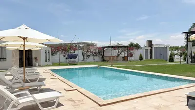a swimming pool with chairs and an umbrella at Casa San José - Bungalow 5 in Ica