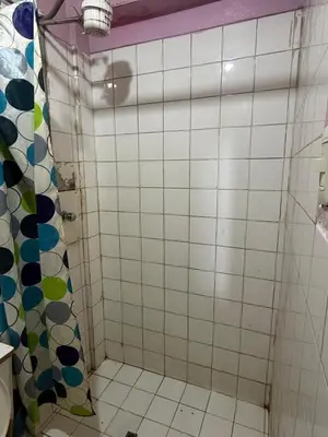 a bathroom with a shower with white tiles at Hospedaje Tarapacá in Huancayo