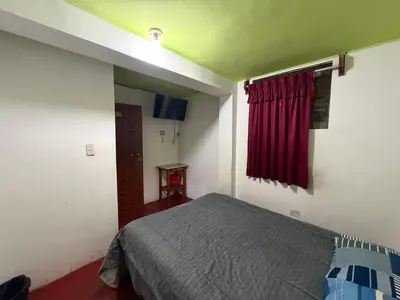 a bedroom with a bed and a red curtain at Hospedaje Tarapacá in Huancayo