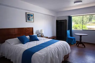 a bedroom with a bed with blue pillows and a window at Mi Hacienda Pacucha in Andahuaylas