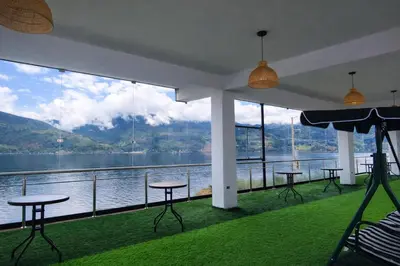 a room with tables and chairs and a view of the water at Mi Hacienda Pacucha in Andahuaylas