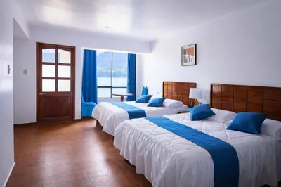 two beds in a hotel room with blue pillows at Mi Hacienda Pacucha in Andahuaylas
