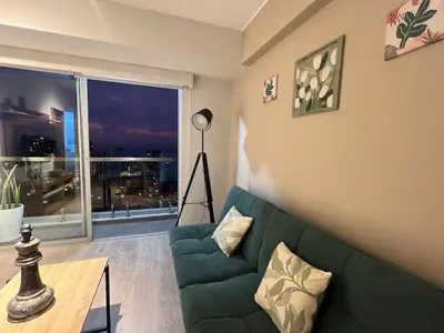 a living room with a green couch and a large window at Barranco apartment facing the ocean in Lima