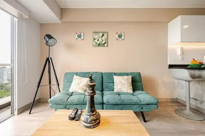 a living room with a green couch and a table at Barranco apartment facing the ocean in Lima