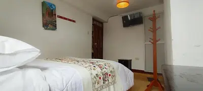 a bedroom with a bed and a cross on the wall at Hospedaje Tikari in Chinchero
