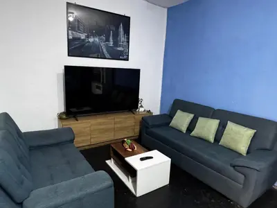 a living room with two blue couches and a tv at Posada Bayoneta in Cusco