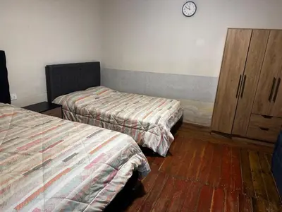 a room with two beds and a wooden cabinet at Posada Bayoneta in Cusco