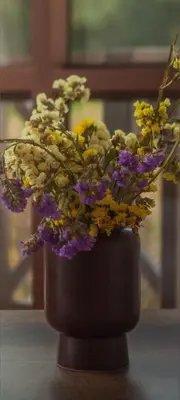 a black vase filled with flowers on a table at Florez de la Villa Apartments in Urubamba