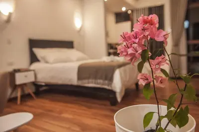 a bedroom with a bed and a vase with pink flowers at Florez de la Villa Apartments in Urubamba
