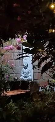 a statue of a buddha sitting in front of a wall at Florez de la Villa Apartments in Urubamba