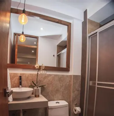 a bathroom with a sink and a toilet and a mirror at Florez de la Villa Apartments in Urubamba