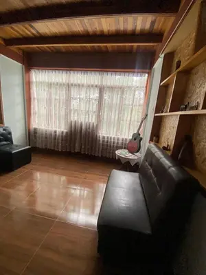 a living room with a couch and a large window at Cabañas Vivenciales La Colina in Oxapampa