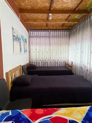 a bedroom with two beds and a window with curtains at Cabañas Vivenciales La Colina in Oxapampa