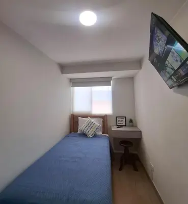 a small bedroom with a bed and a tv at Cómoda habitación con TV a 20 min del aeropuerto in Lima