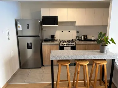a kitchen with a stainless steel refrigerator and bar stools at Cómoda habitación con TV a 20 min del aeropuerto in Lima