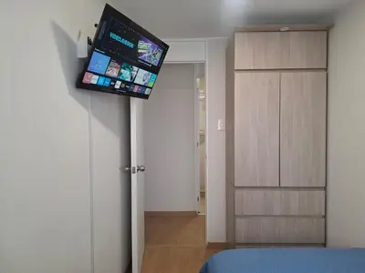 a bedroom with a tv on a wall next to a door at Cómoda habitación con TV a 20 min del aeropuerto in Lima