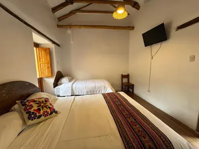 a bedroom with two beds and a flat screen tv at plaza inn in Ollantaytambo
