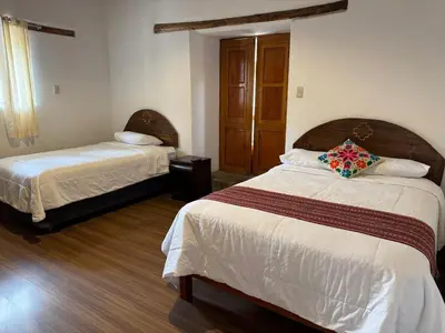 a hotel room with two beds and a window at plaza inn in Ollantaytambo