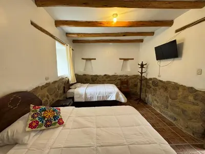 a bedroom with two beds and a tv on the wall at plaza inn in Ollantaytambo