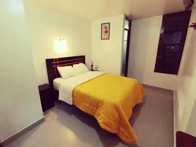 a bedroom with a large bed with a yellow blanket at Destinos Peru Inn - Destinos in Machu Picchu