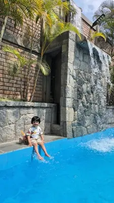 a young child sitting on the edge of a swimming pool at Inka Palace Resort in Santa Eulalia