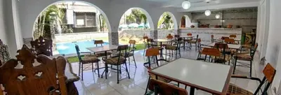 a restaurant with tables and chairs and a pool at Inka Palace Resort in Santa Eulalia