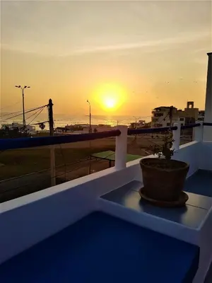 a potted plant sitting on a balcony with the sunset at Waves Surf Camp Peru in Punta Hermosa