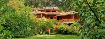 a large wooden house in the middle of a forest at Birds Hotel Molino in Ollantaytambo