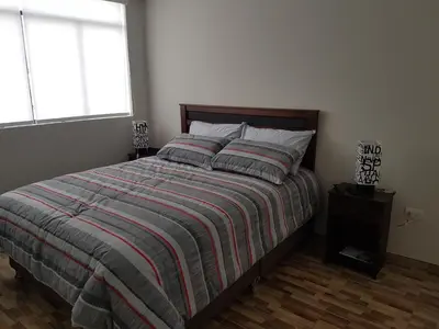 a bedroom with a bed with a striped blanket and a window at Lima Flats in Lima