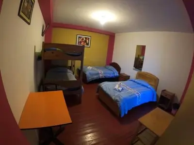 a small room with two beds and a table at Hostel Imperial BACKPACKER in Cusco