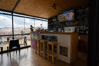 a restaurant with a bar with a view of the mountains at Supertramp Hostel Cusco in Cusco