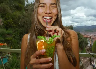 a woman is holding a drink with a fork at Supertramp Hostel Cusco in Cusco