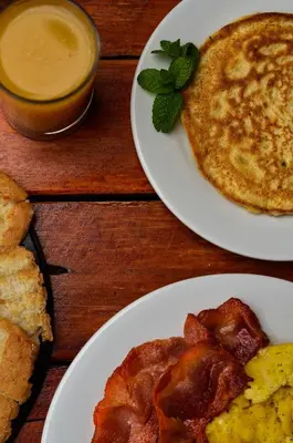 a table with two plates of food with bacon and pancakes at Supertramp Hostel Cusco in Cusco
