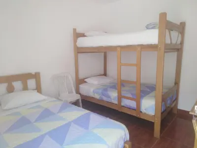 a bedroom with two bunk beds and a chair at Hospedaje El Buen Samaritano in Paracas