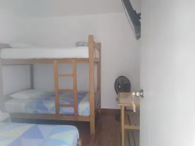a room with two bunk beds and a table at Hospedaje El Buen Samaritano in Paracas