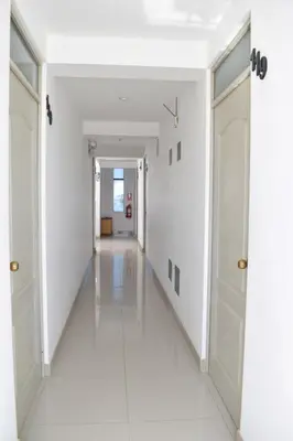 an empty hallway with white walls and white floors at Hospedaje El Buen Samaritano in Paracas