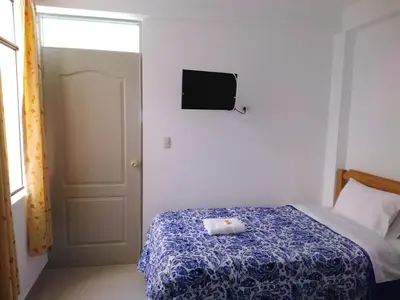 a bedroom with a bed and a tv on the wall at Hospedaje El Buen Samaritano in Paracas