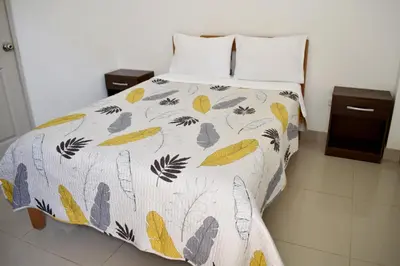 a bed with a comforter with leaves on it at Hospedaje El Buen Samaritano in Paracas